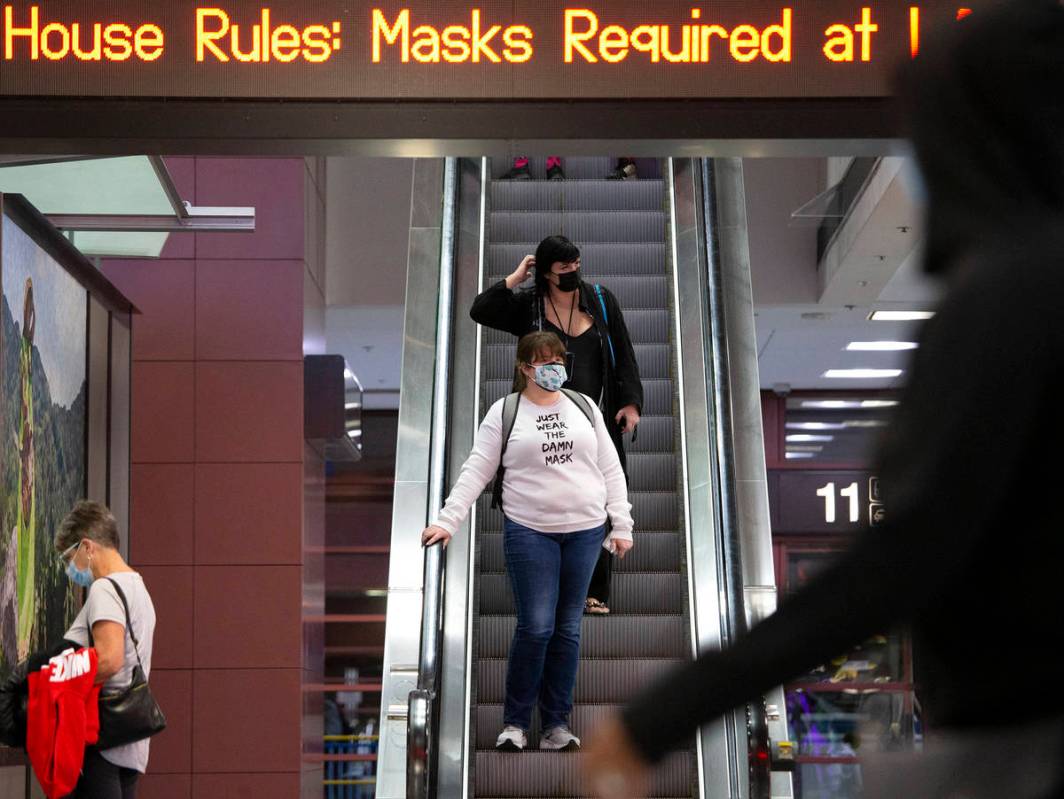 Visitors to Las Vegas enter baggage claim, wearing personal protective equipment to prevent the ...