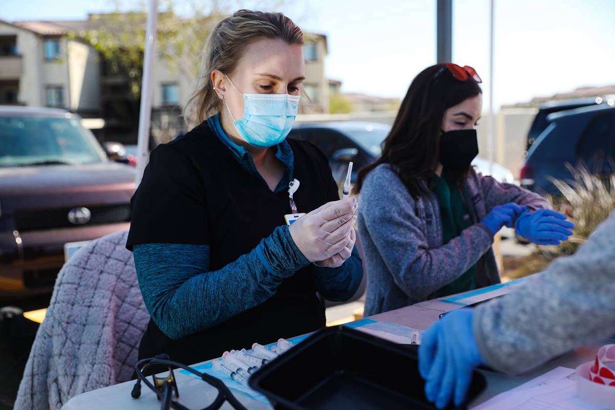 Physician assistant student Erica Moran, left, preps COVID-19 vaccines next to fellow physician ...