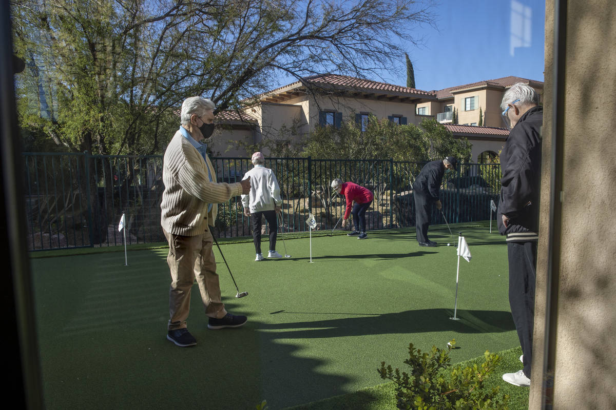 Seniors enjoy the community's newly installed putting green with their families and friends dur ...