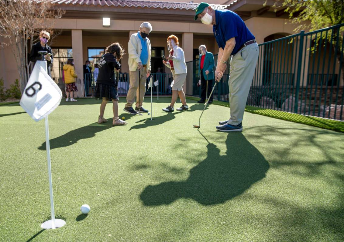 Gene Sajcich eyes a putt on the community's newly installed putting green during a special even ...