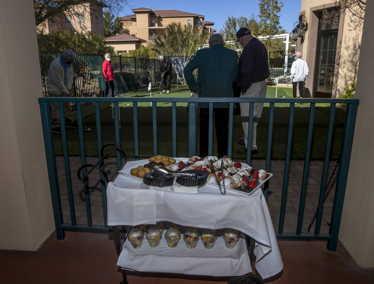 Seniors enjoy the community's newly installed putting green and breakfast treats during a speci ...