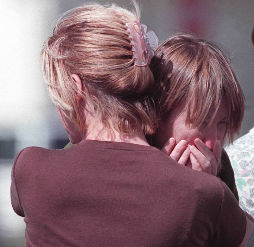 A crisis intervention specialist (back to camera) hugs an Albertsons employee in the parking lo ...