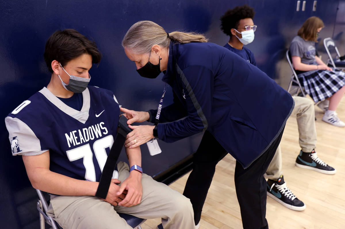 Athletic Trainer Kim Jacobs uses a COVID-19 screening device on student-athlete Zack Ramsey at ...