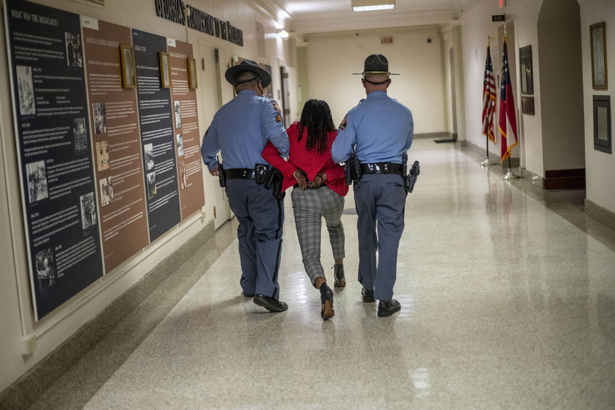 Rep. Park Cannon (D-Atlanta) is escorted out of the Georgia Capitol by Georgia state troopers a ...