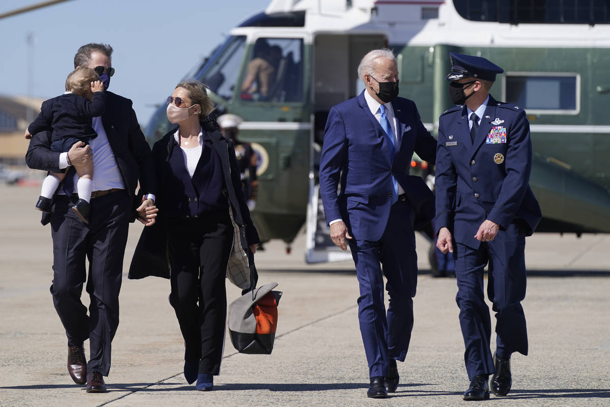 President Joe Biden walks with his son Hunter Biden, left, as Hunter carries his son Beau and h ...