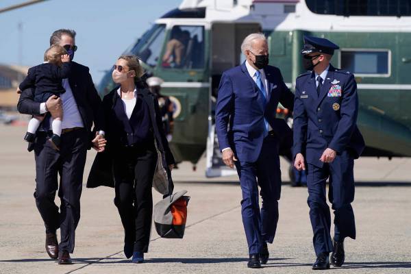 President Joe Biden walks with his son Hunter Biden, left, as Hunter carries his son Beau and h ...