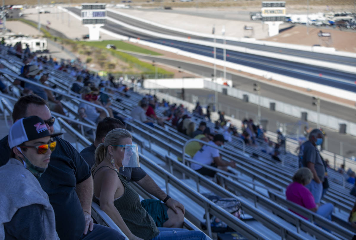 Some fans wear personal protective equipment while watching the Dodge NHRA Finals at Las Vegas ...