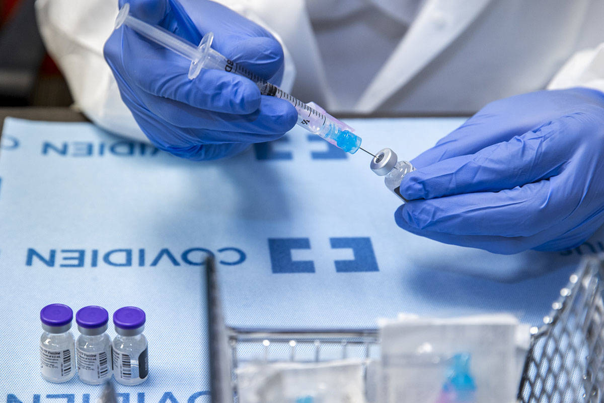 Student pharmacist Wilbur Quimba loads up new syringes with vaccine as University Medical Cente ...