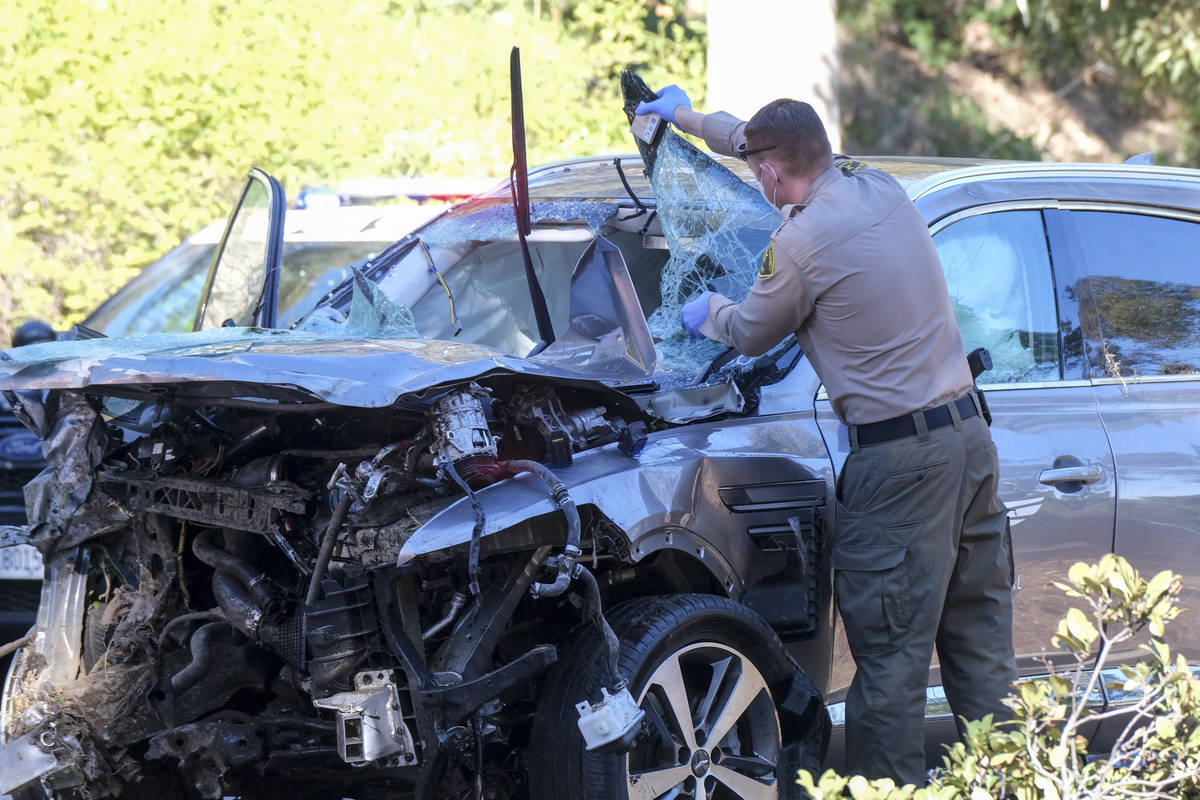 A law enforcement officer looks over a damaged vehicle following a rollover accident involving ...