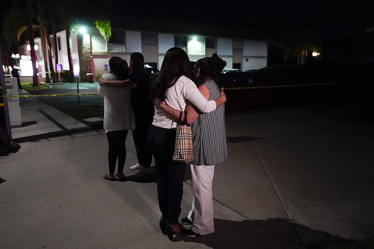 Unidentified people comfort each other as they stand near a business building where a shooting ...