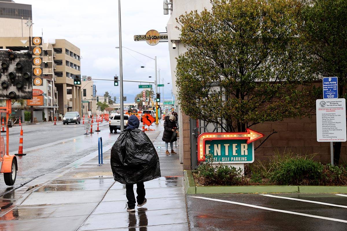 A pedestrian uses a trash bag to protect himself from rain on Las Vegas Boulevard near Fremont ...