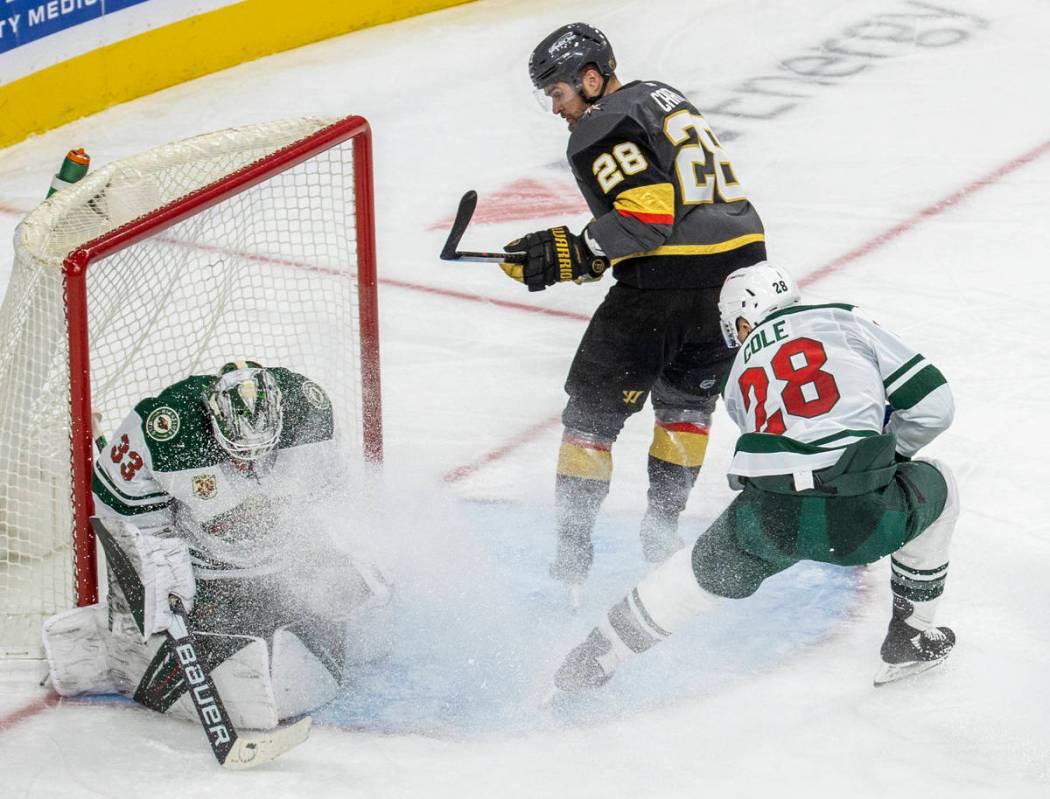 Minnesota Wild goaltender Cam Talbot (33) traps a shot on goal by a driving Golden Knights left ...