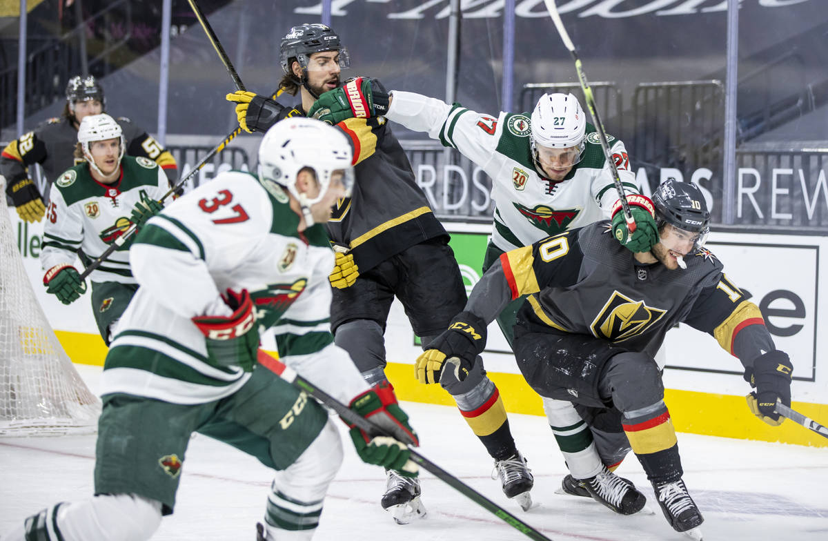 Golden Knights defenseman Nicolas Hague (14, center) and teammate Golden Knights center Nicolas ...