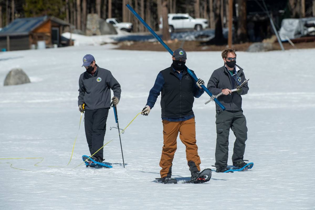 Aided by John Paasch, left, and Anthony Burdock, right, Sean de Guzman, chief of snow surveys f ...