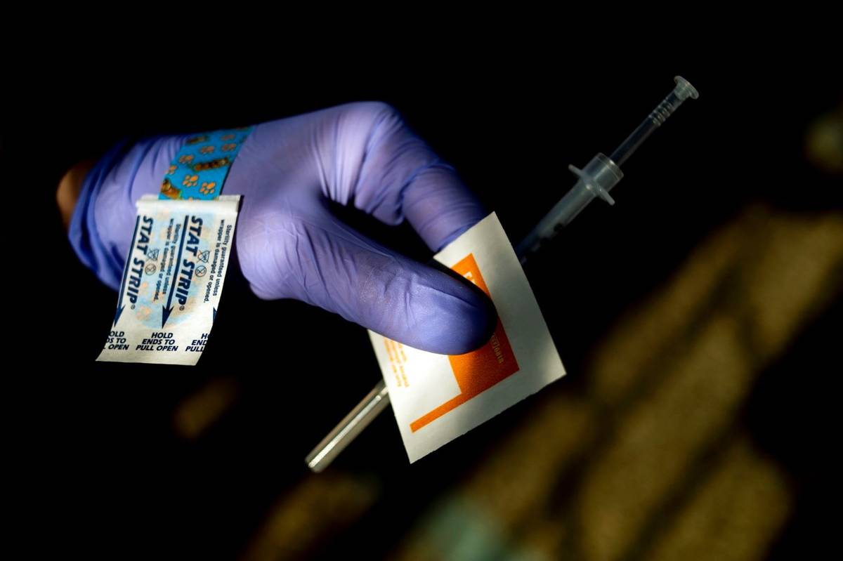 A nursing student helps administer the first dose of the Moderna COVID-19 vaccine to residents ...