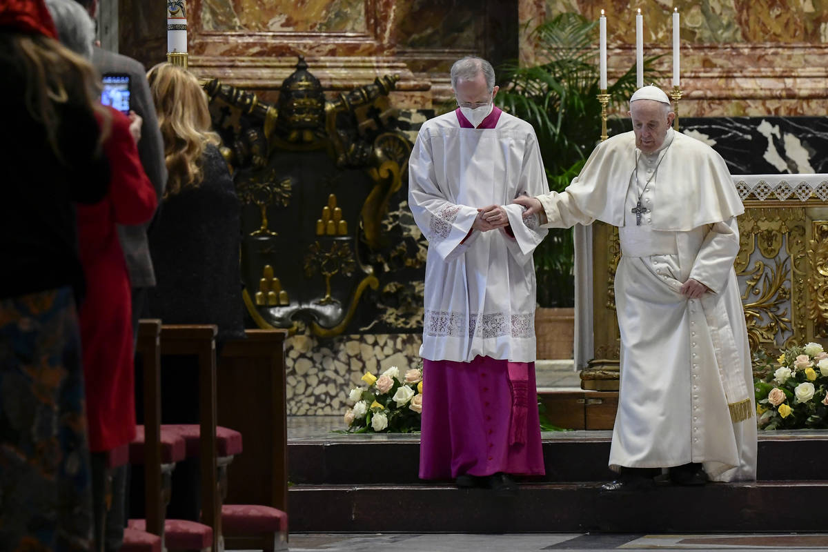 Master of Pontifical Liturgical Ceremonies, Italian priest Guido Marini helps Pope Francis step ...