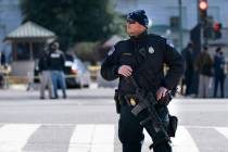 A Capitol Police officer patrols with a rifle at the site where a car crashed into a barrier on ...
