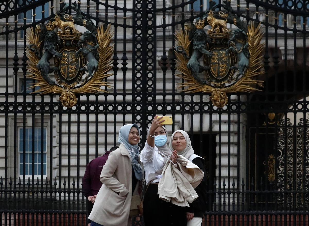 Tourists pose for selfies in front of the gates of Buckingham Palace in London, Monday, April 5 ...