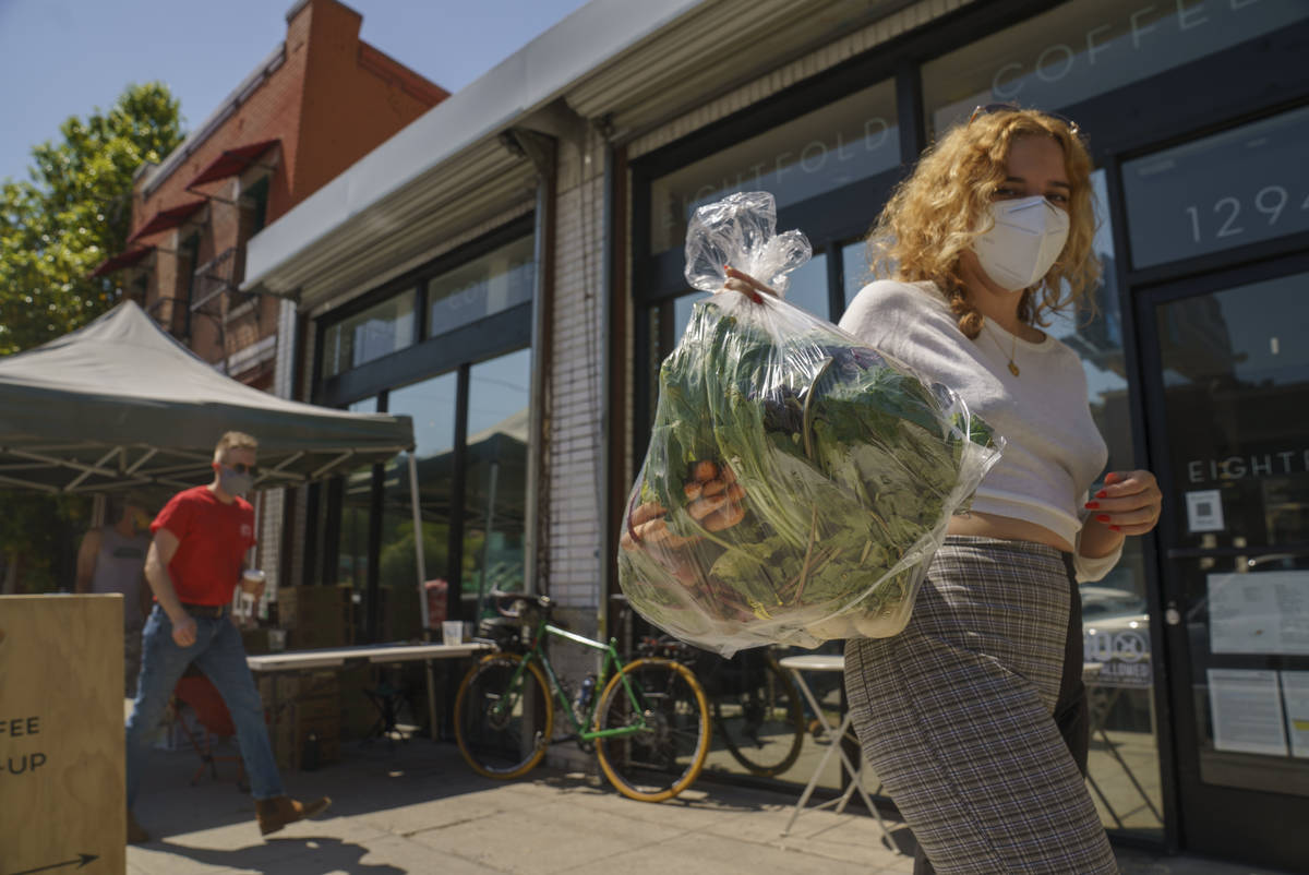 Fashion designer Josie Vand wears a facemask as she retrieves a bag with organic vegetables fro ...