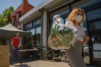 Fashion designer Josie Vand wears a facemask as she retrieves a bag with organic vegetables fro ...