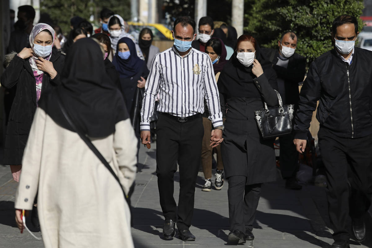 People wearing protective face masks to help prevent the spread of the coronavirus walk in down ...