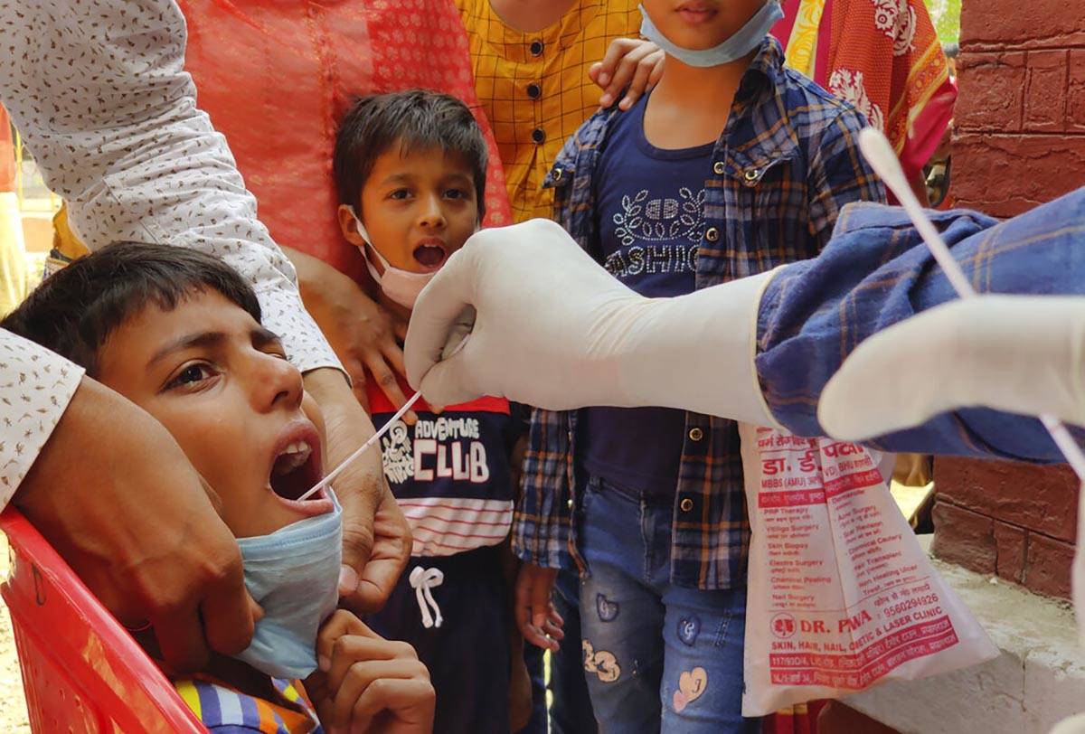 A health worker takes swab sample of children to test for COVID-19 in Prayagraj, India, Thursda ...