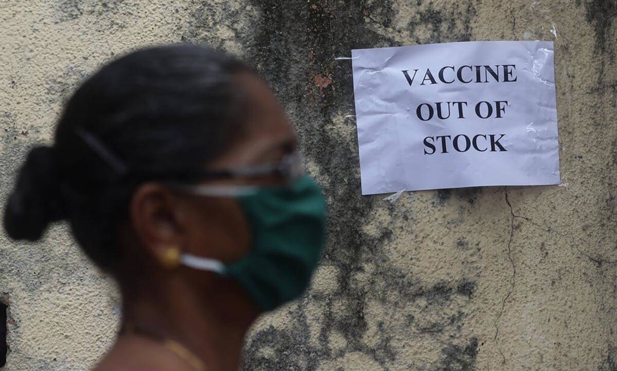 A woman wearing mask walks past a notice about the shortage of coronavirus (COVID-19) vaccine s ...
