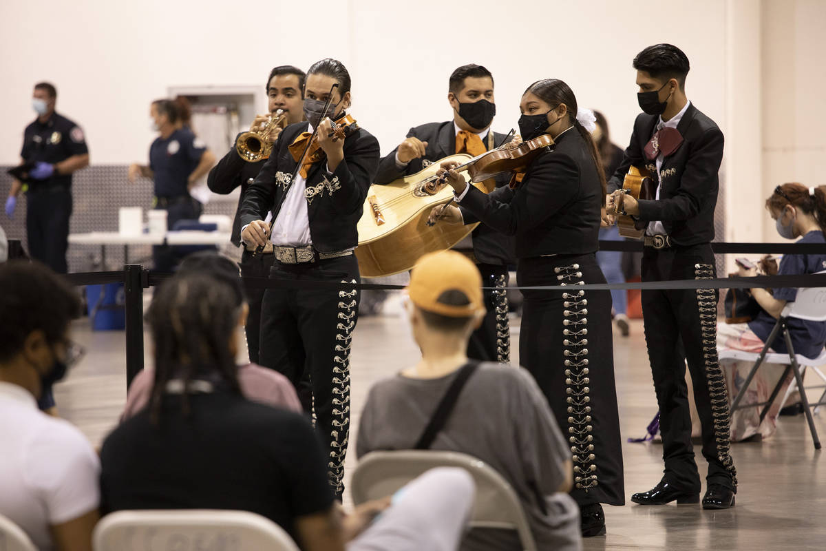 Mariachi Nuestras Raices performs to a room of people waiting in line for COVID-19 vaccines or ...