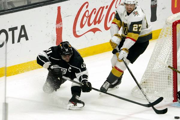 Los Angeles Kings center Anze Kopitar, left, falls as he moves the puck while under pressure fr ...