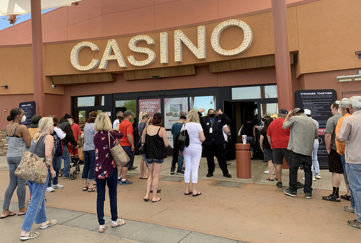Players walk into Gila River Casino's Lone Butte location after waiting in line due to max capa ...