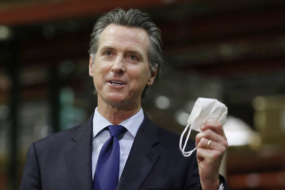 In this June 26, 2020, file photo, California Gov. Gavin Newsom holds a face mask during a news ...