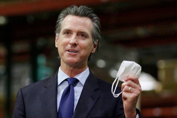 In this June 26, 2020, file photo, California Gov. Gavin Newsom holds a face mask during a news ...