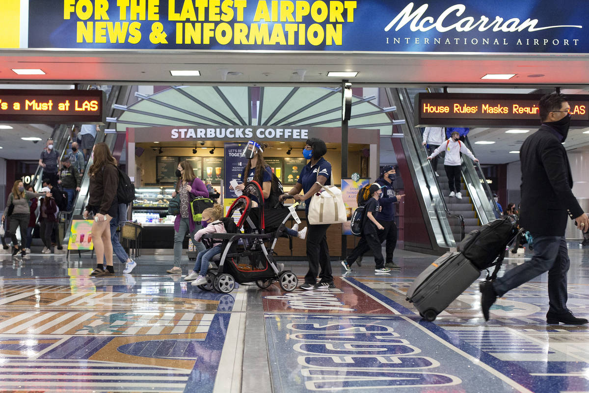 People move throughout baggage claim, wearing personal protective equipment to prevent the spre ...
