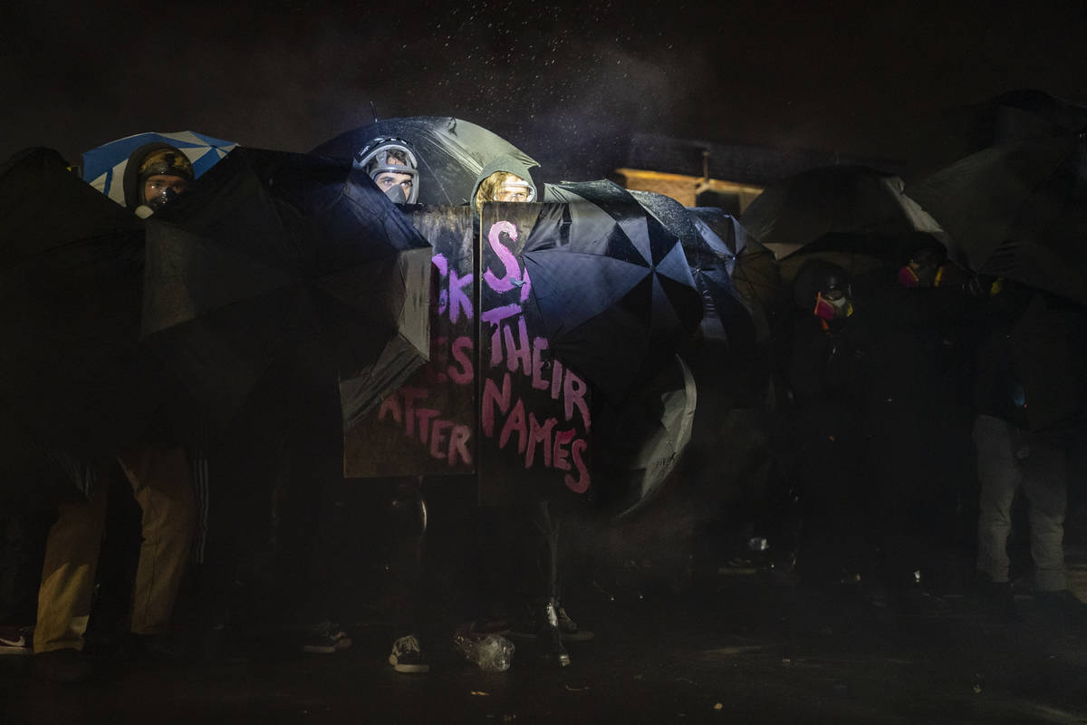 Demonstrators use umbrellas as shields Tuesday, April 13, 2021, outside the Brooklyn Center (Mi ...