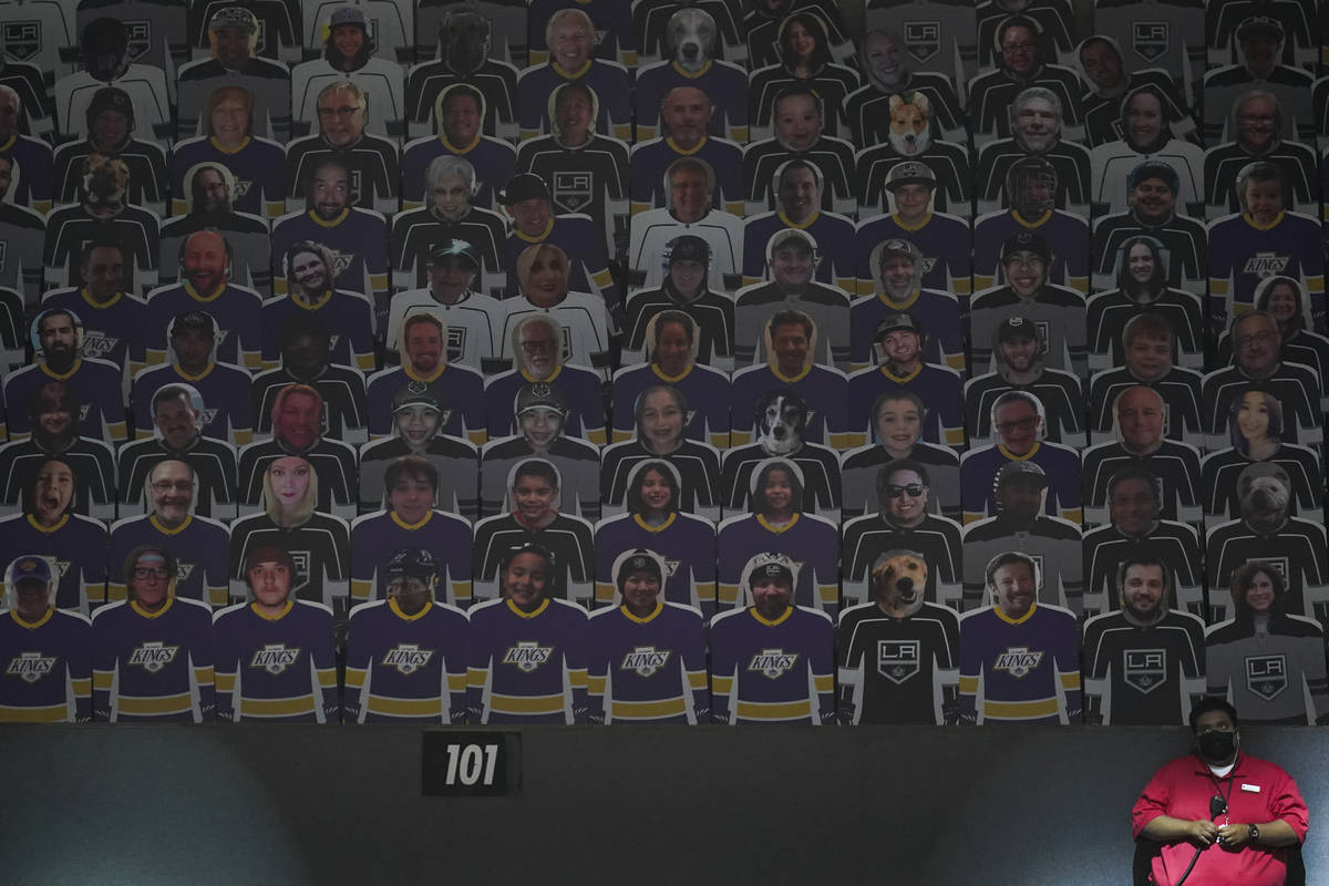 An usher stands next to a section of cutouts of fans in the stands at an NHL hockey game betwee ...