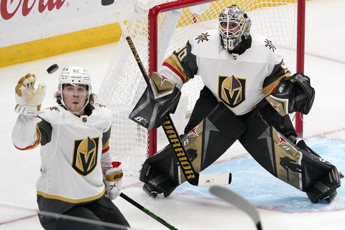Vegas Golden Knights defenseman Dylan Coghlan, left knocks the puck out of the air as goaltende ...