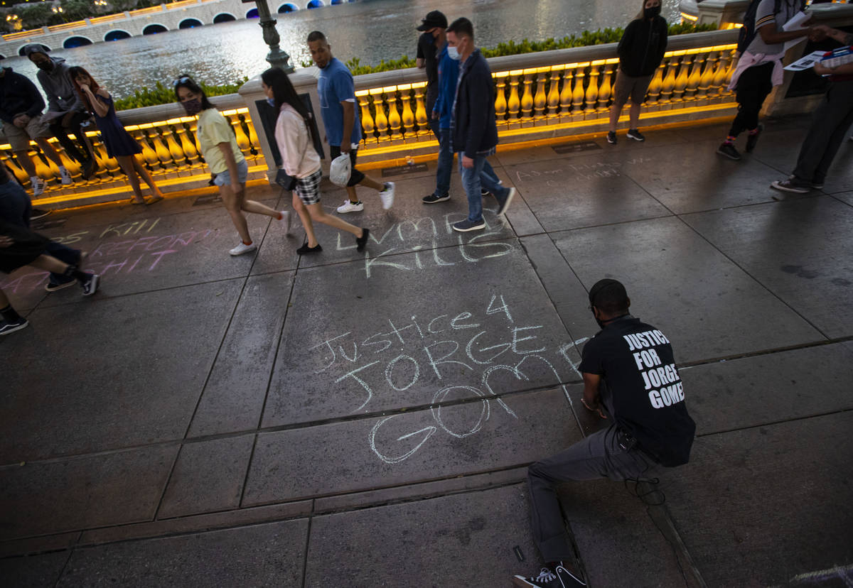 A man who declined to provide his name writes in chalk on the sidewalk outside of the Bellagio ...