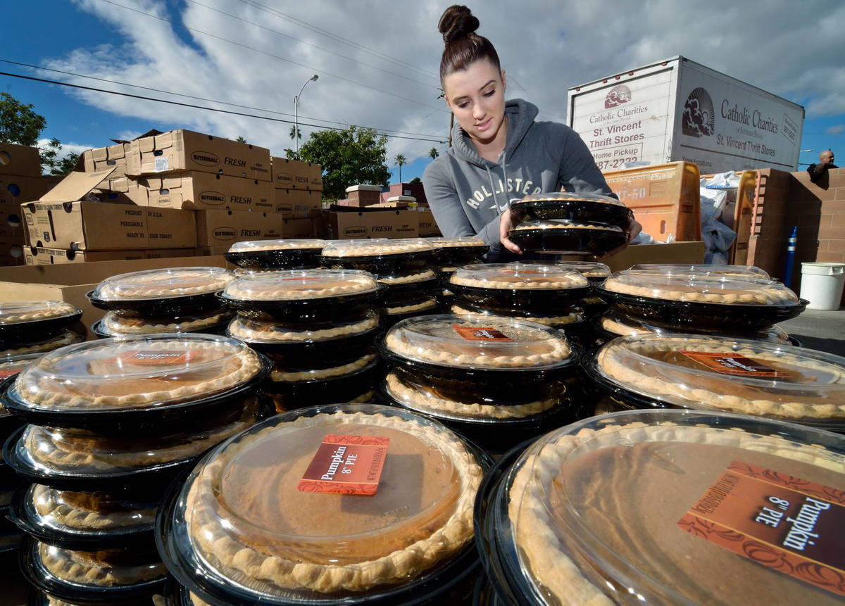 Volunteer Kaylei Dunn stacks pumpkin pies during a Thanksgiving food giveaway at Catholic Chari ...