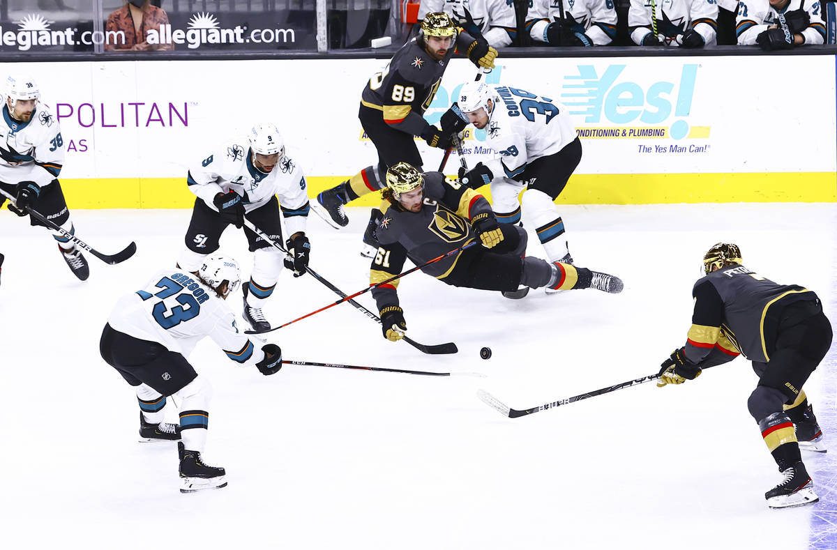 Golden Knights' right wing Mark Stone (61) gets tripped up between San Jose Sharks' left wing E ...