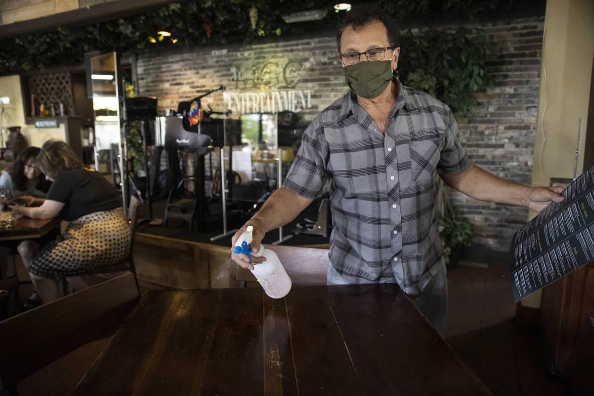Joe Pierro, owner of Market Grille Cafe, cleans a table before seating customers. Despite offer ...