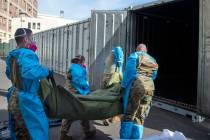 National Guard members, assisting with processing COVID-19 deaths, place bodies into temporary ...