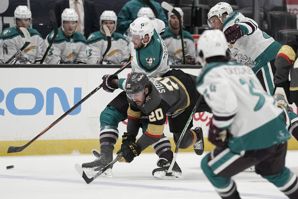 Vegas Golden Knights' Chandler Stephenson, center, loses his balance as he fights for the puck ...