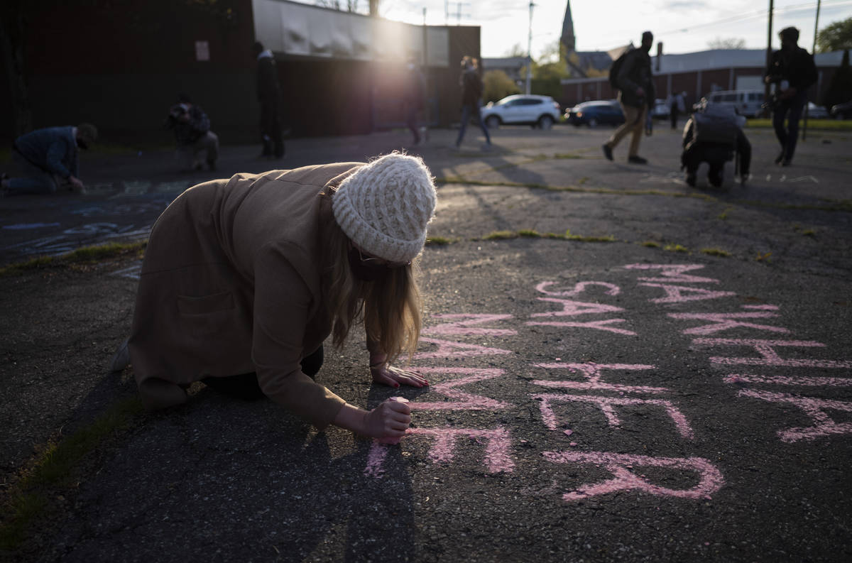 Haley Fielding writes out "Ma'Khia Say Her Name" in chalk before the start of a commu ...