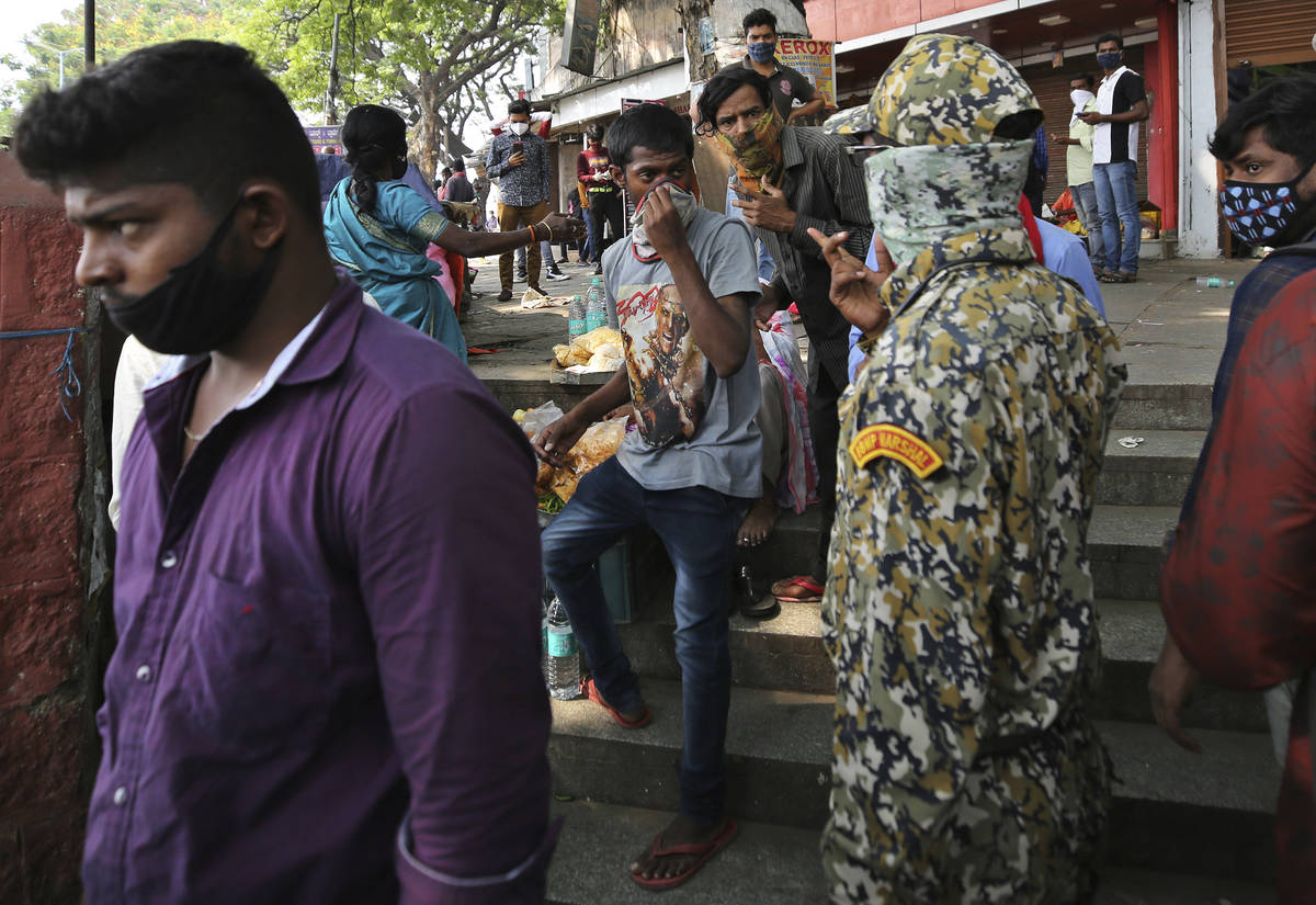 A municipal official, second right, reprimands street vendors for not wearing face masks proper ...