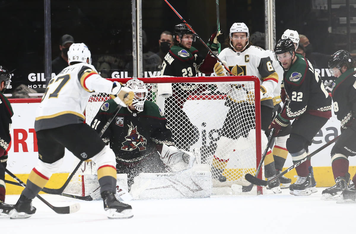 Arizona Coyotes goaltender Adin Hill (31) and forward Johan Larsson (22) defend the net as Gold ...