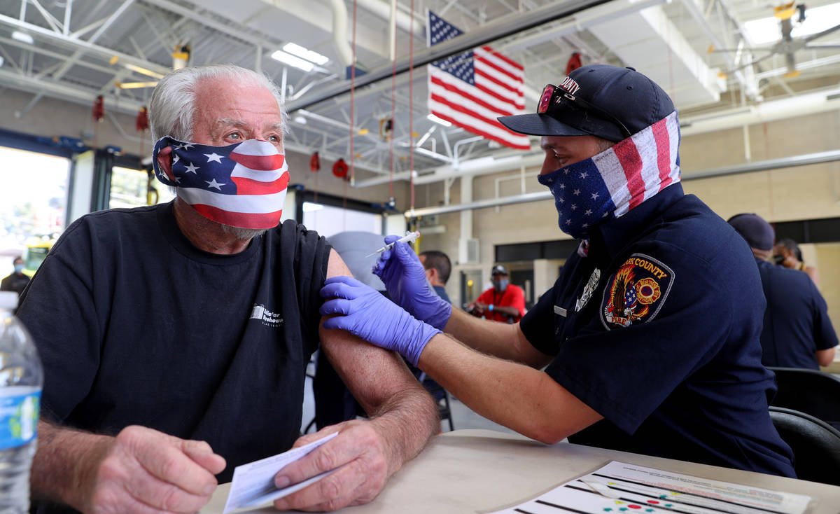 Clark County Fire Department firefighter Matt Sambol gives a COVID-19 vaccination to Don Lyon, ...