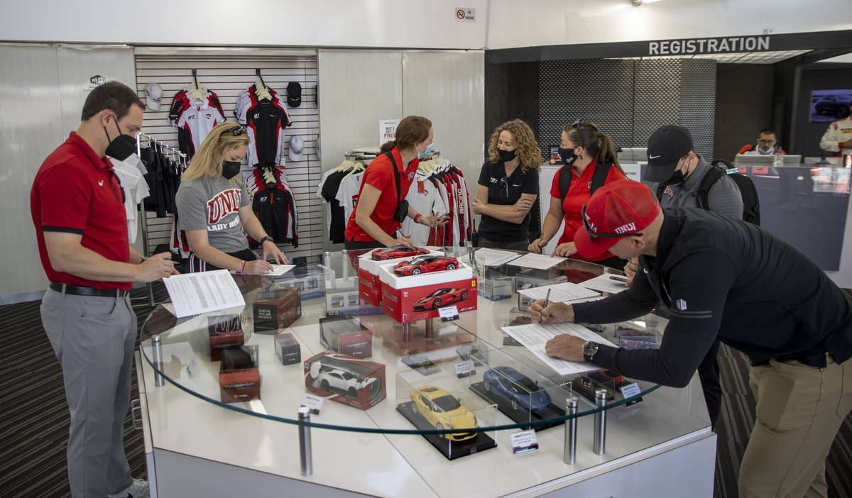 UNLV coaches fill out paperwork as they bring their Rebel Caravan to Dream Racing at the Las Ve ...