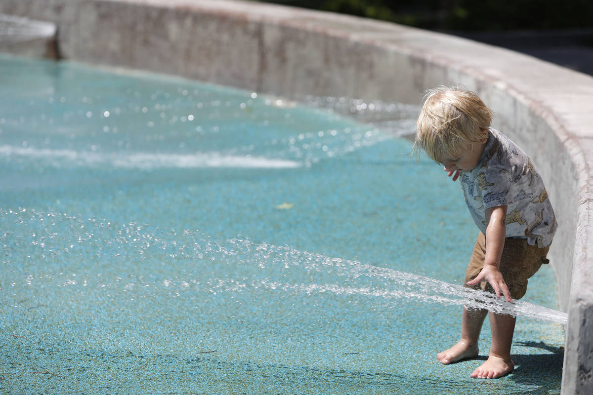 Aegis Burris, 1, of Summerlin touches the water at the Paseos Park splash pad in Las Vegas, Sat ...