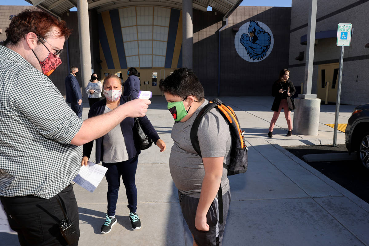 Counselor Lucas Partridge helps sixth grader Gael Marin on the first day of in-person education ...