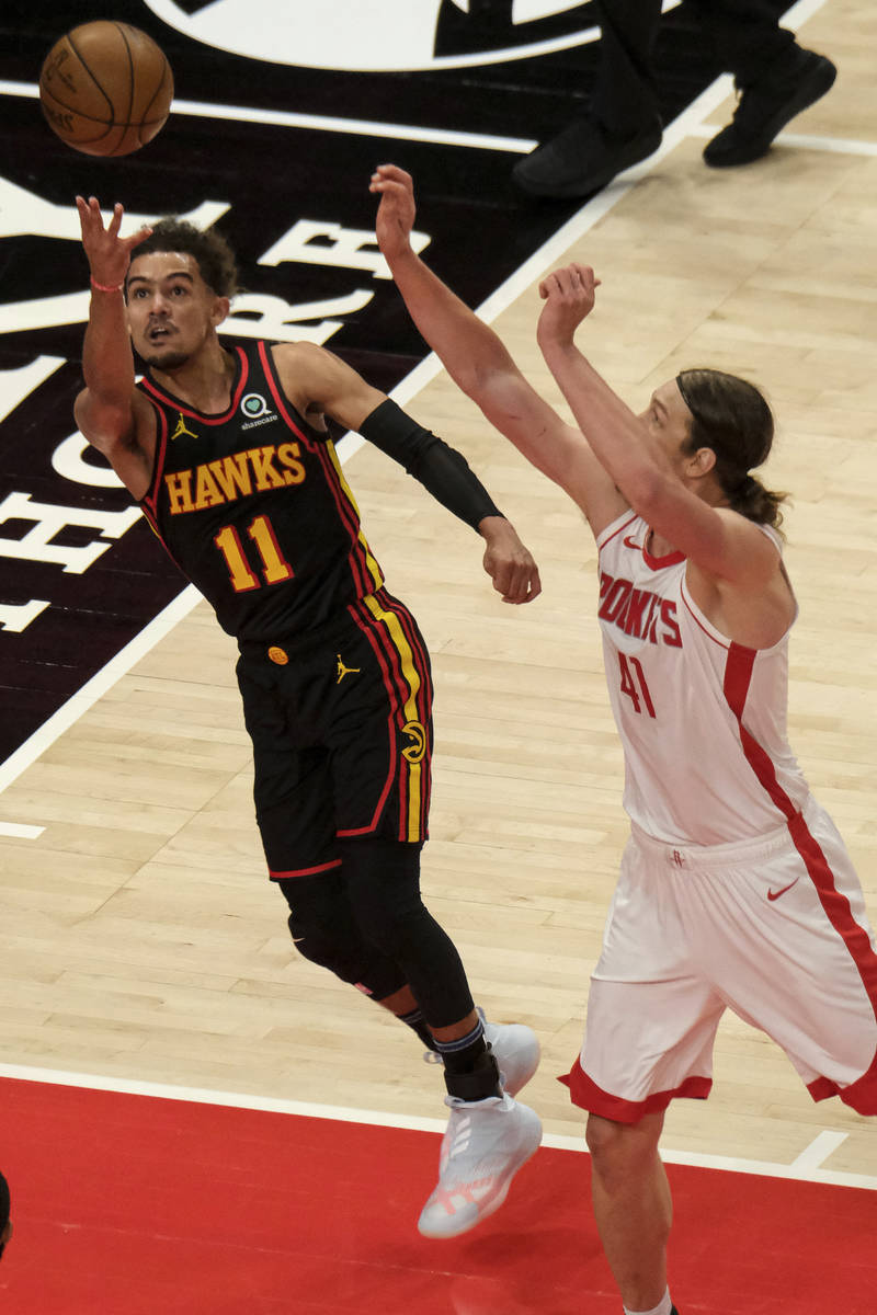 Atlanta Hawks guard Trae Young (11) shoots as Houston Rockets forward Kelly Olynyk (41) rushes ...